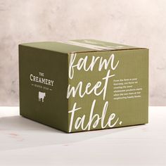 a green box with white lettering on the front and bottom that says farm meet table