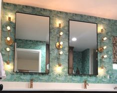 a bathroom with three mirrors and lights on the wall