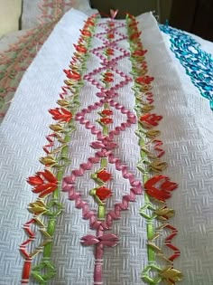 an embroidered table runner with red, pink and green flowers on it's edges