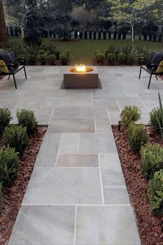 an outdoor fire pit surrounded by plants and chairs with the words inspire written on it