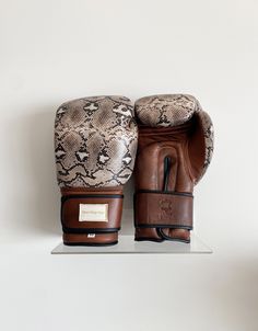 a pair of brown leather gloves sitting on top of a white shelf next to a wall