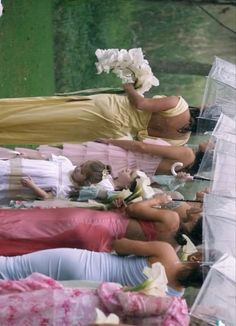 several women laying on the ground with umbrellas over their heads and flowers in their hair