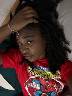 a woman laying on top of a bed wearing a spider man t - shirt with her hair in the air