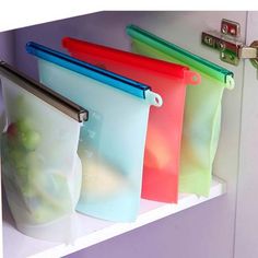 four different colored zipper bags hanging on a white wall next to a mirror and sink