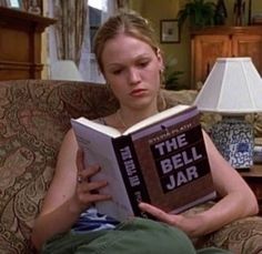 a woman sitting on a couch reading a book