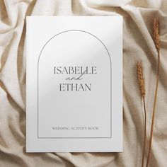 a wedding activity book on a bed with white linens and dried flowers in the background