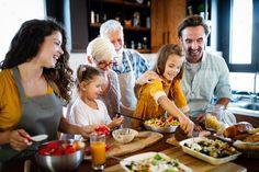 a group of people standing around a table with food