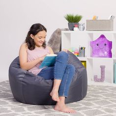 a woman sitting on a bean bag chair reading a book