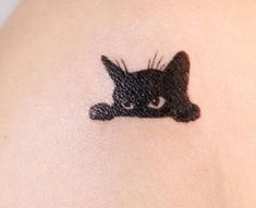 a small black cat tattoo on the back of a woman's left arm,