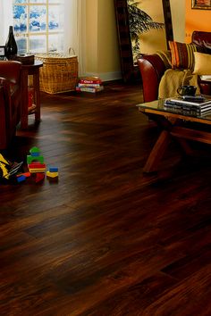 a living room filled with furniture and lots of wood flooring next to a window