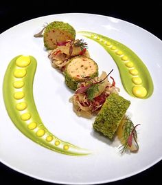 a white plate topped with food on top of a green and yellow sauce covered dish