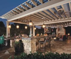 an outdoor kitchen and dining area is lit up at night with lights on the roof