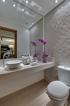 a white toilet sitting next to a sink in a bathroom under a mirror with lights