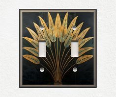 a decorative light switch plate cover with gold leaves on black and white background, in the shape of a palm tree