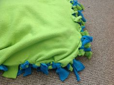 a green and blue blanket laying on the floor