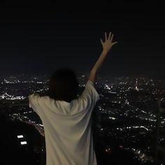 a person standing on top of a hill with their arms in the air at night