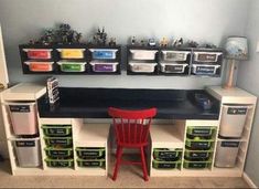 a desk with several bins and a red chair