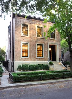 a large brick house with many windows and bushes in front of the entrance to it