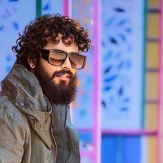 a man with curly hair wearing sunglasses and a jacket