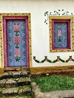 two doors with flowers painted on them are in front of a white wall and steps