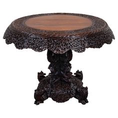 an ornately carved wooden table with intricate carvings on the top and bottom, against a white background