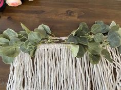 a close up of a piece of cloth with leaves and flowers on the table next to it