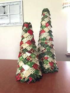 two small christmas trees sitting on top of a wooden table