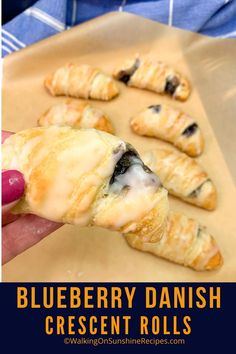 blueberry danish made with refrigerator crescent rolls on parchment paper and being held by a woman