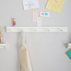 a white coat rack with clothes hanging from it's hooks and pegs on the wall