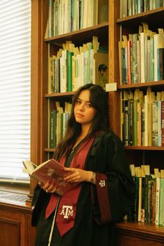 a woman standing in front of a bookshelf holding a book