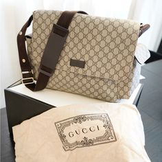 a gucci bag sitting on top of a table next to a white box with a brown strap