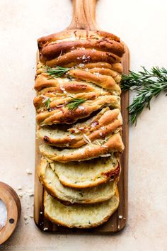 sliced bread on a cutting board with rosemary sprigs