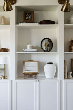 a white shelf filled with books and vases