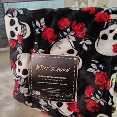 a black and white blanket with red roses on it that has a skull in the middle