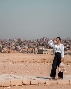 a woman standing on top of a stone slab in front of a cityscape