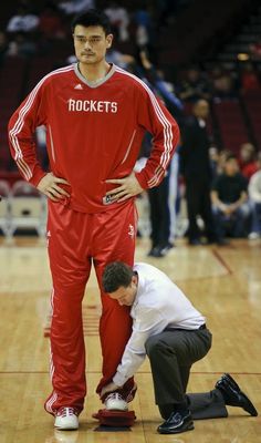 two men in red and white uniforms standing on a basketball court with their hands on the ground