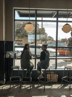 two people sitting at a table in front of a window looking out on the parking lot