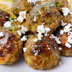 meatballs with feta cheese and lemon wedges on a white plate, ready to be eaten