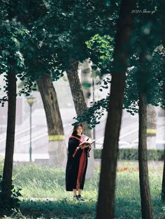 a woman standing in the woods reading a book