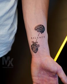 a person with a tattoo on their arm that says balance and a heart in the middle