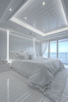 a large white bed sitting in the middle of a bedroom next to a tall window