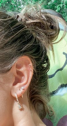 a close up of a person wearing some kind of earring with grass in the background