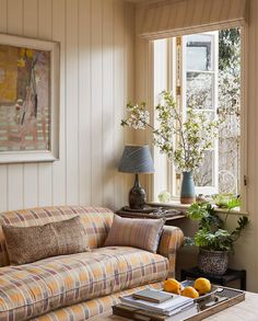 a living room filled with furniture and a painting on the wall next to a window