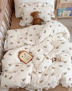 a teddy bear sitting on top of a bed next to pillows and blankets in a child's room