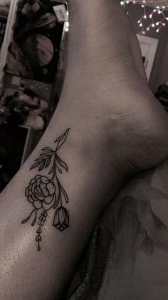 a woman's foot with a tattoo on it and flowers in the middle of her leg