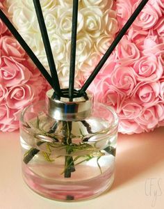 a vase filled with flowers and reeds on top of a table next to pink roses