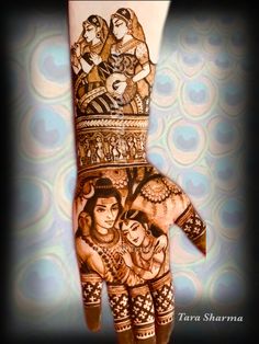 a woman's hand painted with henna and images of people on the palm