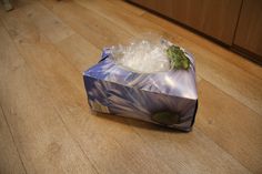 a wrapped present sitting on top of a wooden floor next to a counter with ice cubes in it