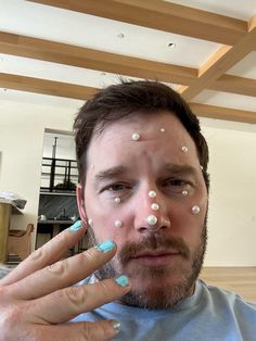 a man with white dots on his face and fingers in front of him, making the shape of a heart