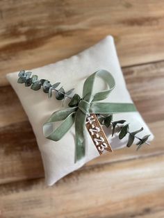 a white pillow with a green ribbon tied around it on top of a wooden floor